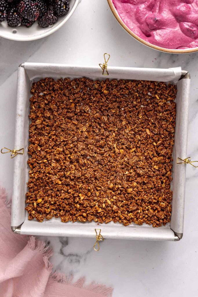 Baked granola crust for blackberry cobbler bars cooling in pan