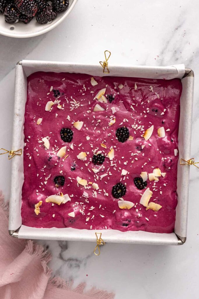 Finishing blackberry cobbler bars with coconut flakes