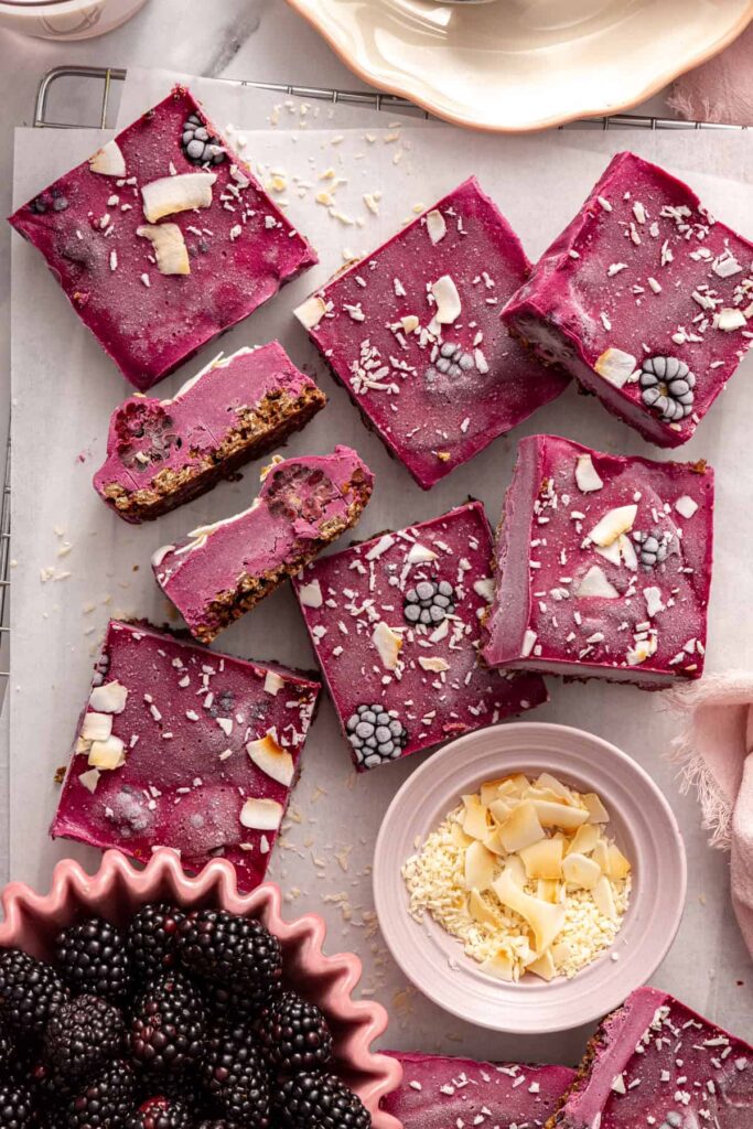 Frozen blackberry cobbler bars on table with fresh blackberries and coconut