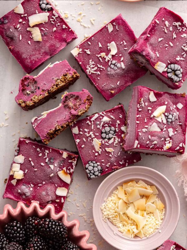 Frozen blackberry cobbler bars on a parchment-lined wire rack with fresh blackberries and shredded coconut