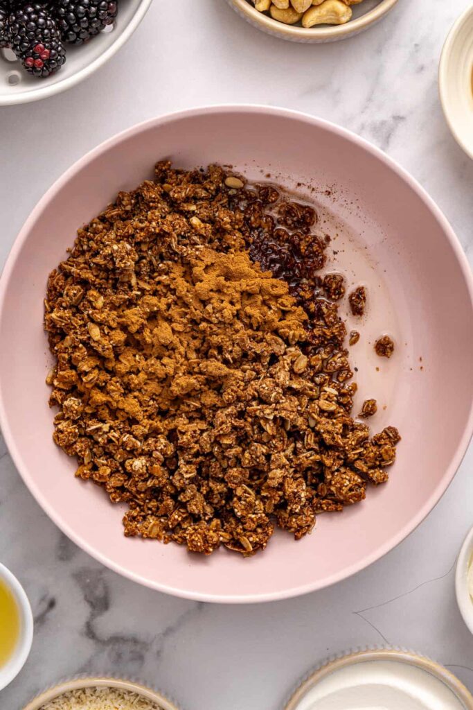 Granola mixed with melted coconut oil and cinnamon for blackberry cobbler bars crust