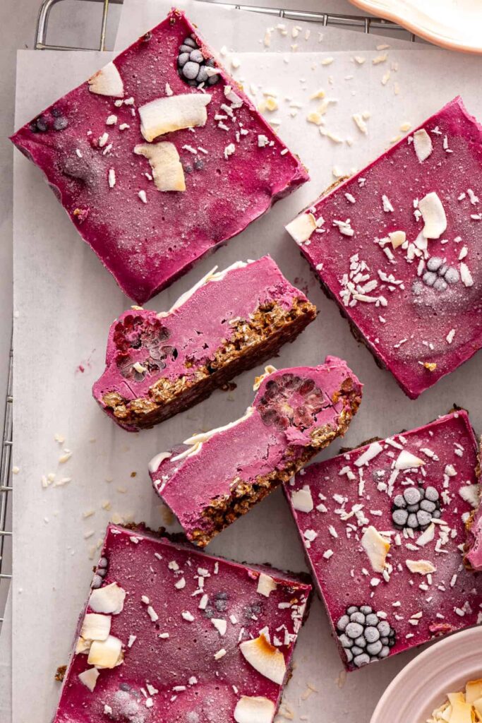 Overhead of frozen blackberry cobbler bars on parchment-lined rack