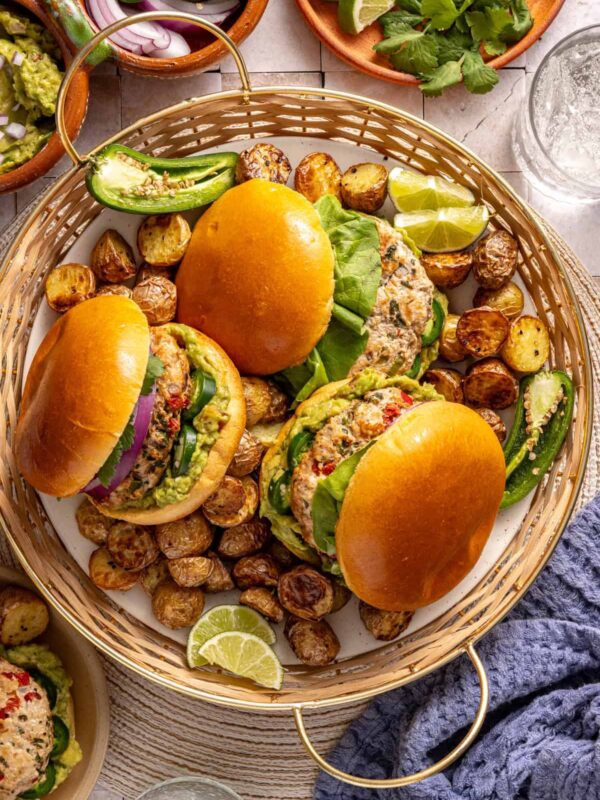 Jalapeño burgers plated with fresh toppings and sides on a summer tablescape