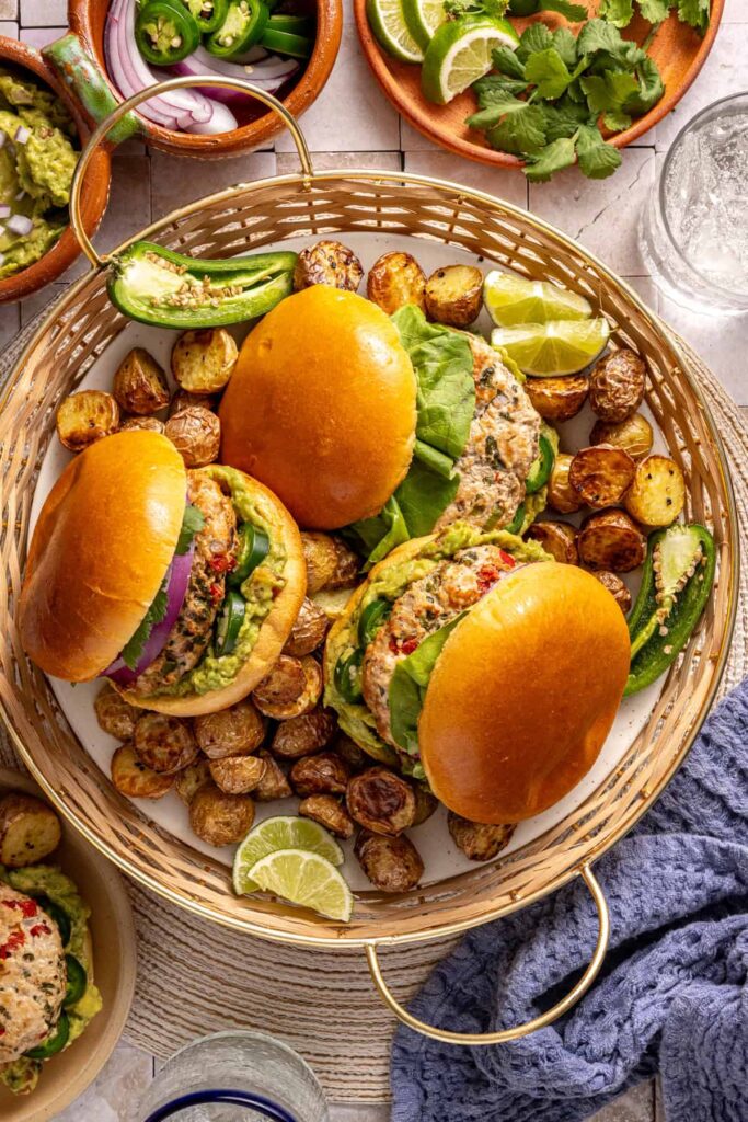 Jalapeรฑo burgers plated with fresh toppings and sides on a summer tablescape