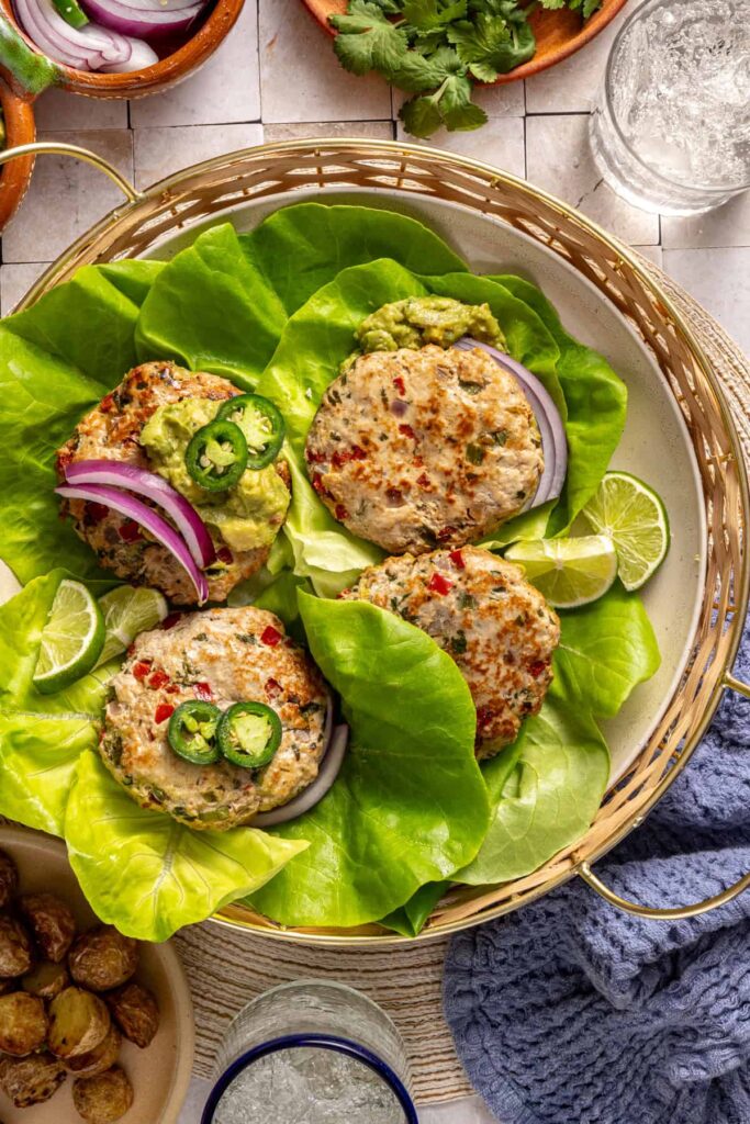 Finished jalapeño burgers served in lettuce cups with garnishes