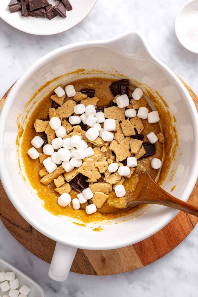 Folding chocolate chips, marshmallows and graham cracker pieces into cookie dough