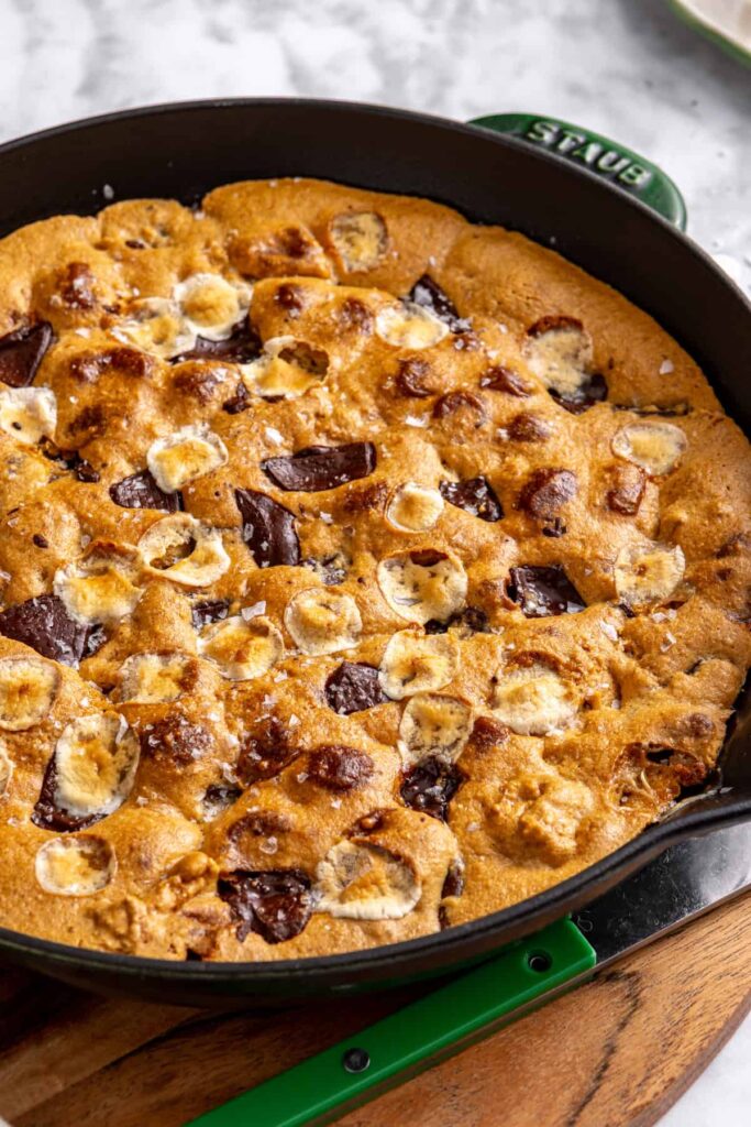 Freshly baked s'mores cookie skillet resting on a cutting board