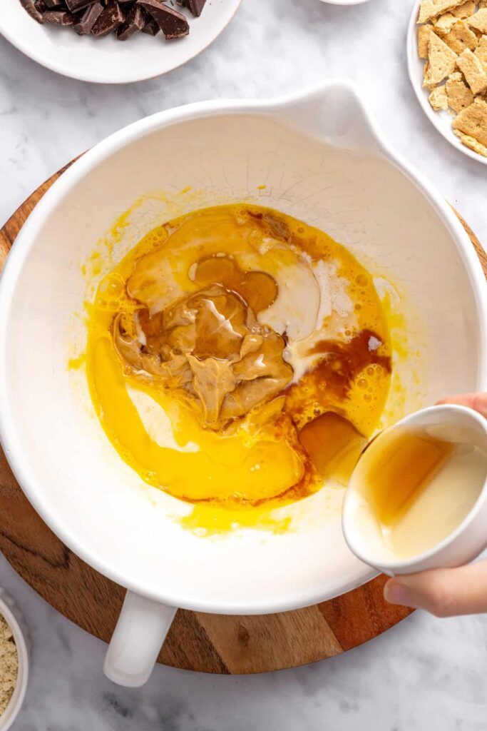pouring vanilla extract into wet ingredient mixture for gluten-free s'mores cookie skillet