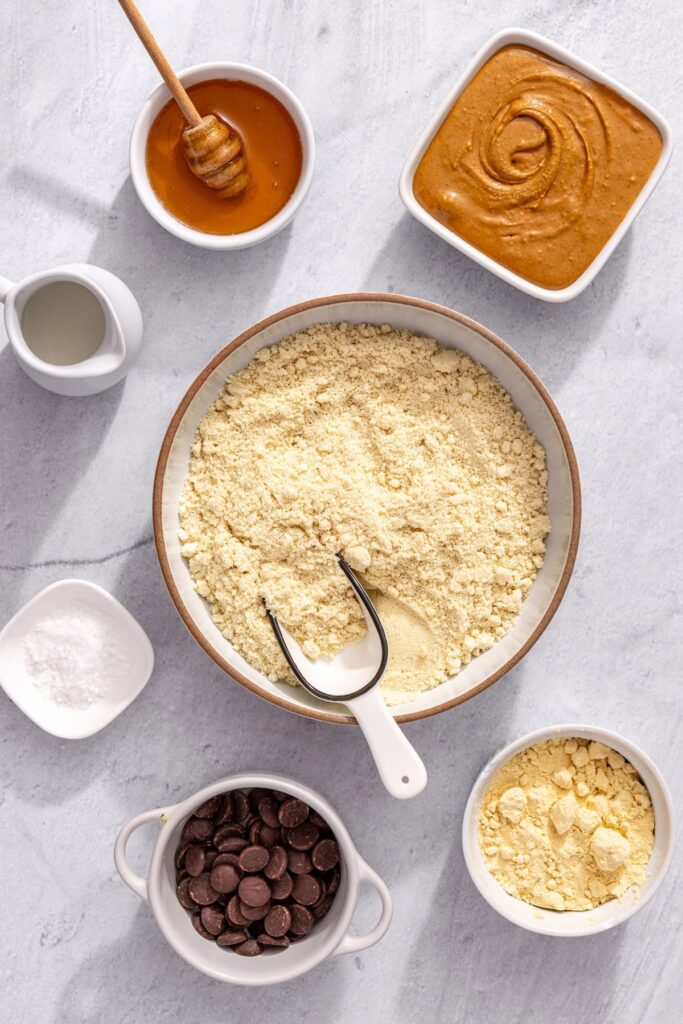 overhead shot of almond flour, peanut butter, honey, protein powder, and chocolate chips to make no-bake protein bars