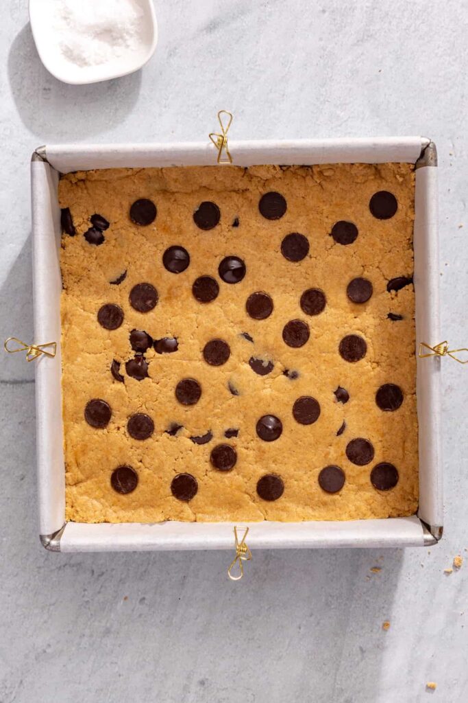 Sprinkling chocolate chips over peanut butter protein bars before chilling