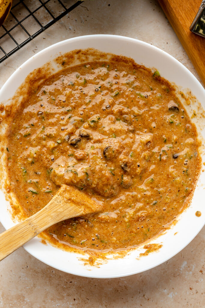 Grated zucchini being folded into gluten-free zucchini bread batter