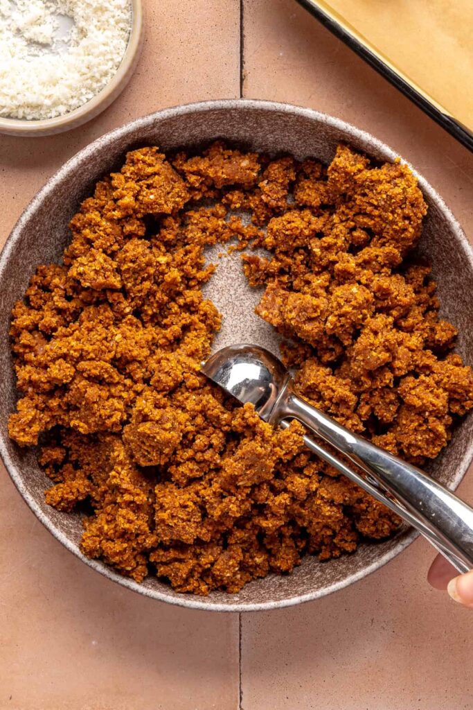Scooping pumpkin purée, almond butter, and pecans to make pumpkin protein balls