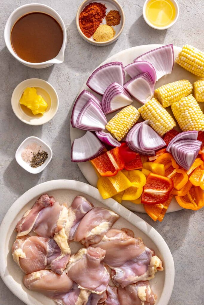 Ingredients for grilled teriyaki chicken with corn, bell peppers, red onion, teriyaki sauce, and seasonings