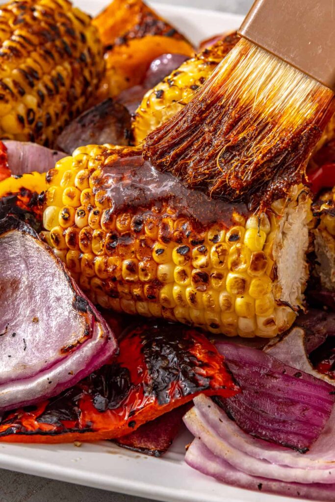 Close-up of seasoned ghee brushed onto grilled corn