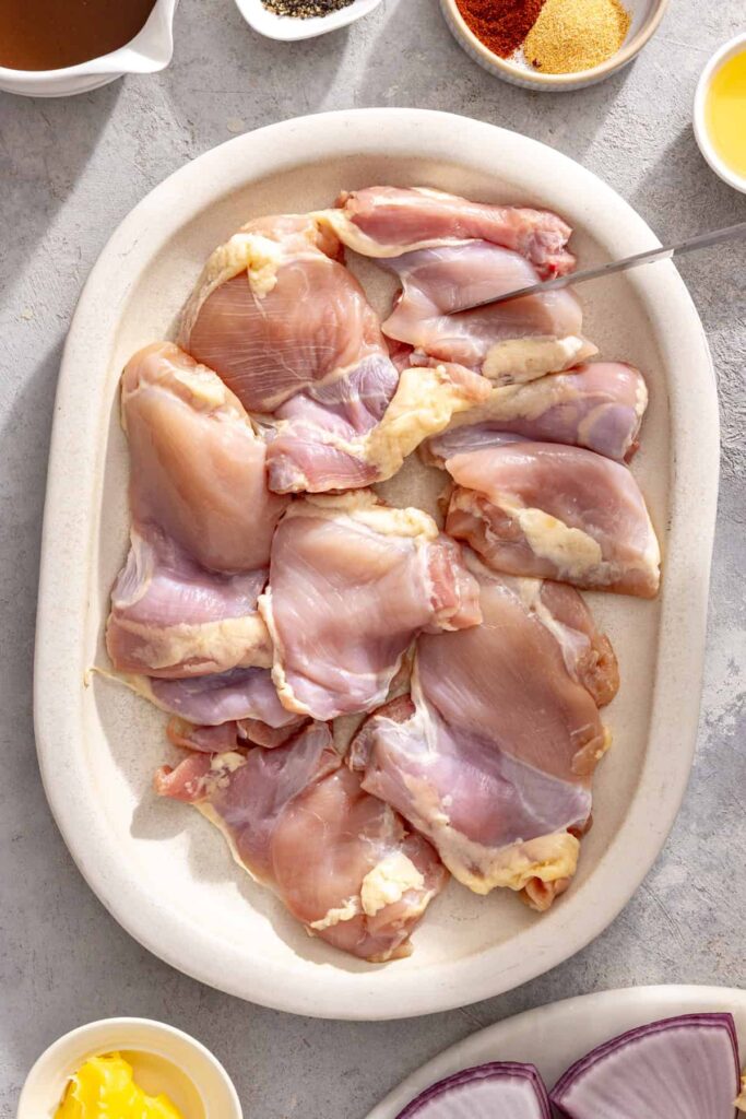 chicken thighs in a bowl, ready to be seasoned, for grilled teriyaki chicken and vegetables