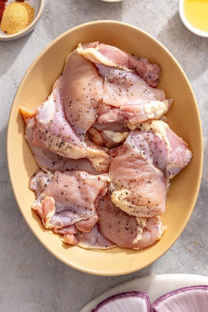 seasoned chicken thighs in a bowl, ready to marinate in teriyaki sauce