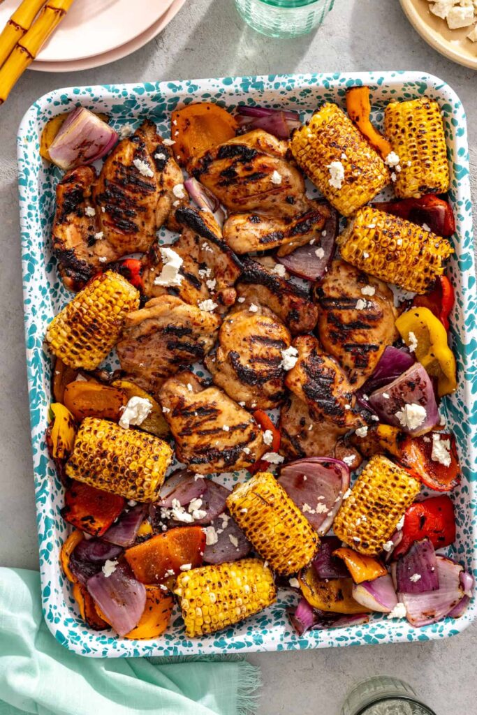 Teriyaki chicken served with grilled vegetables and feta cheese on a styled table