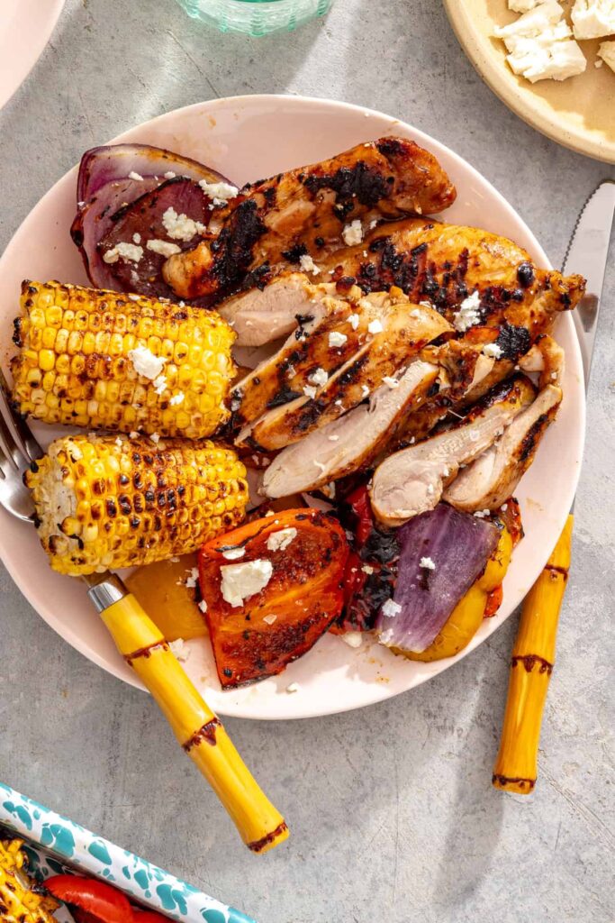 Individual serving of grilled teriyaki chicken with grilled vegetables and corn