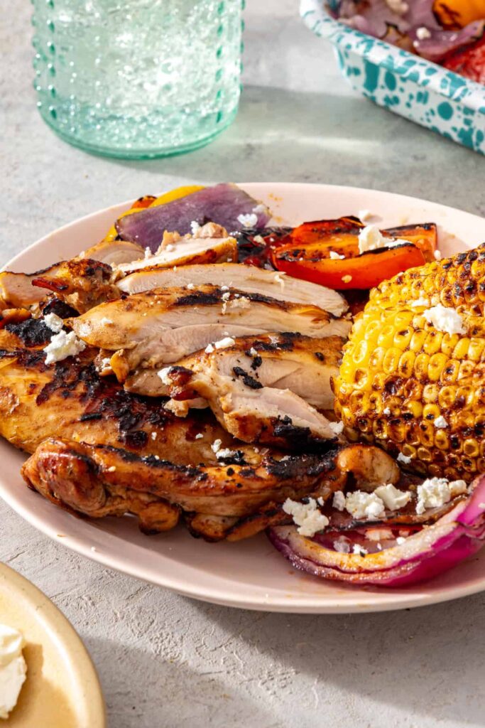 Grilled teriyaki chicken with grilled vegetables and corn served on a plate