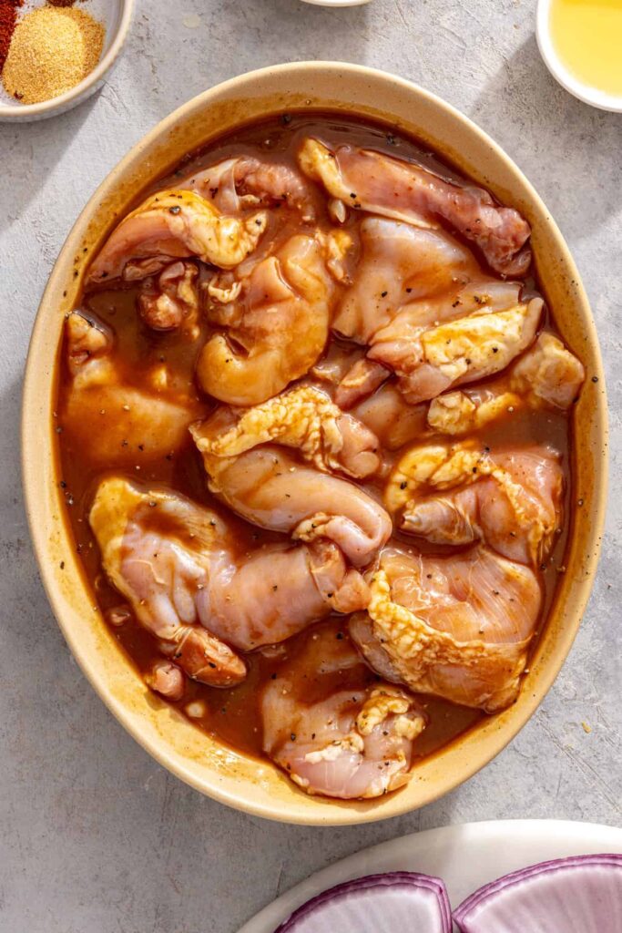 Chicken thighs marinating in teriyaki sauce before grilling