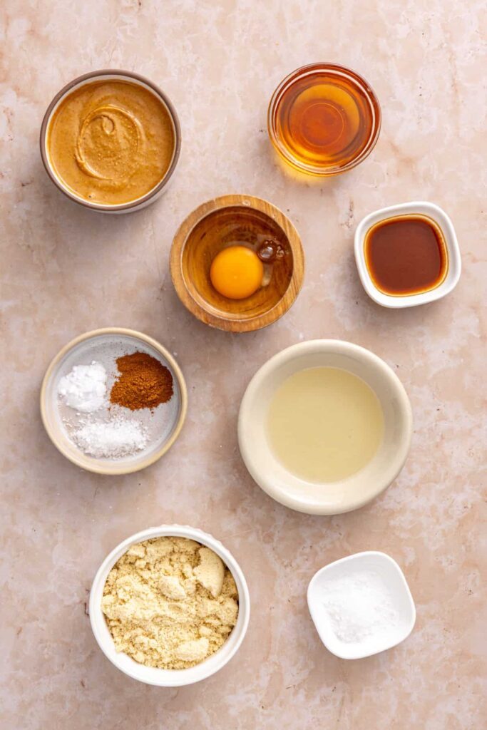 Gluten-free peanut butter cookie ingredients including peanut butter, almond flour, maple syrup, egg, coconut oil, vanilla, cinnamon and baking soda