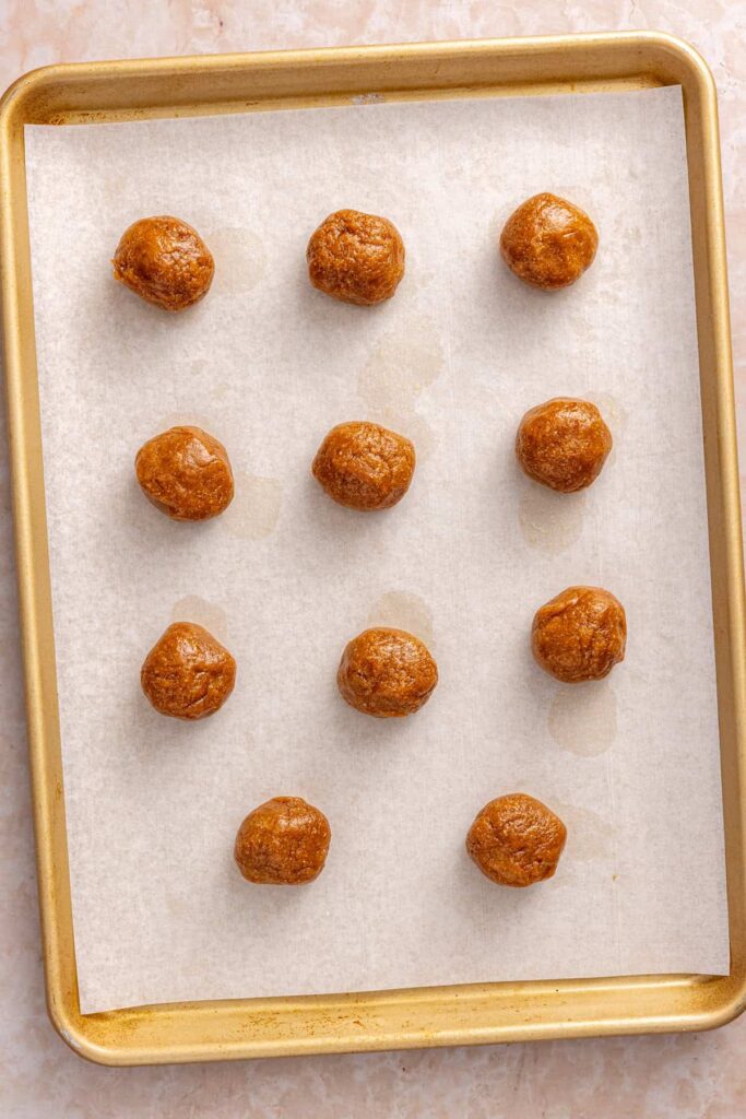 Scoops of gluten-free peanut butter cookie dough portioned onto a parchment-lined baking sheet