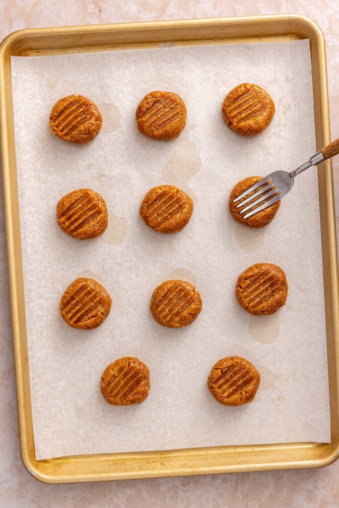 Fork pressed into gluten-free peanut butter cookie dough to create a classic crisscross pattern