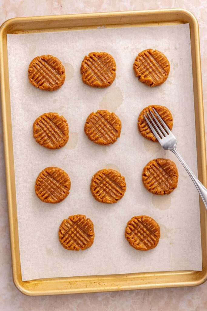 Shaping peanut butter cookies with a fork before baking