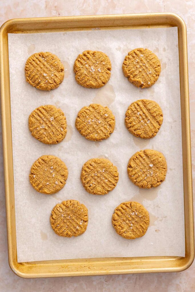 Freshly baked gluten-free peanut butter cookies cooling on a baking sheet