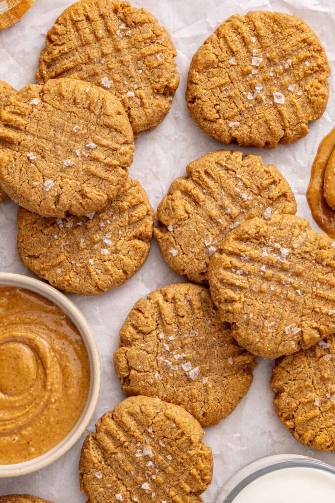 Healthy gluten-free peanut butter cookies arranged on a table with peanut butter and milk