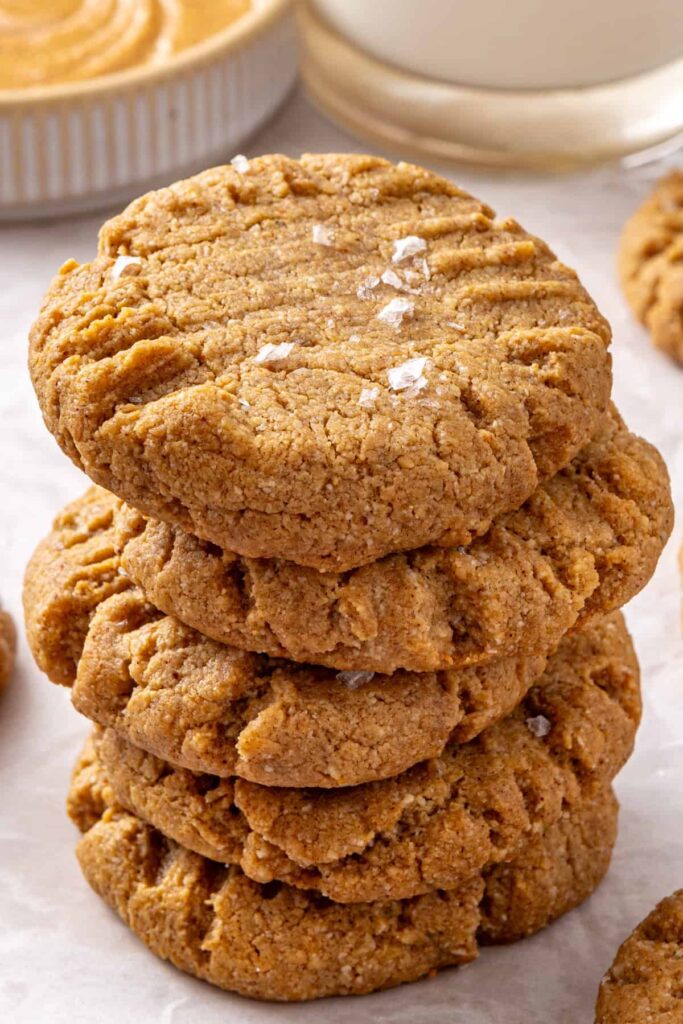Homemade peanut butter cookies stacked high with a glass of milk