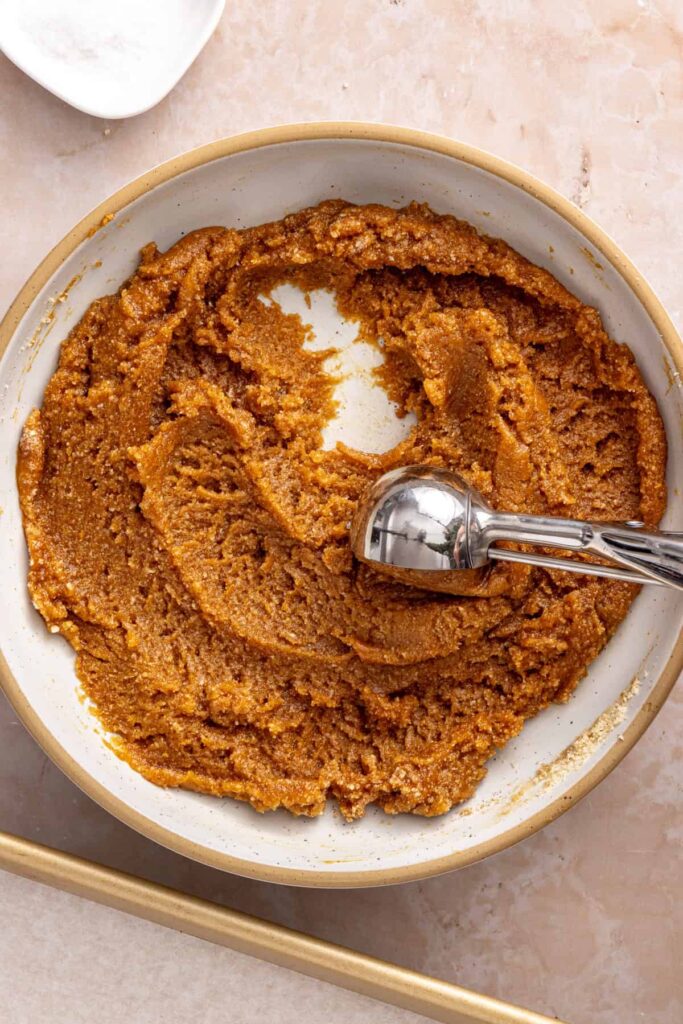 using a cookie scoop to scoop gluten-free peanut butter cookie dough from a mixing bowl