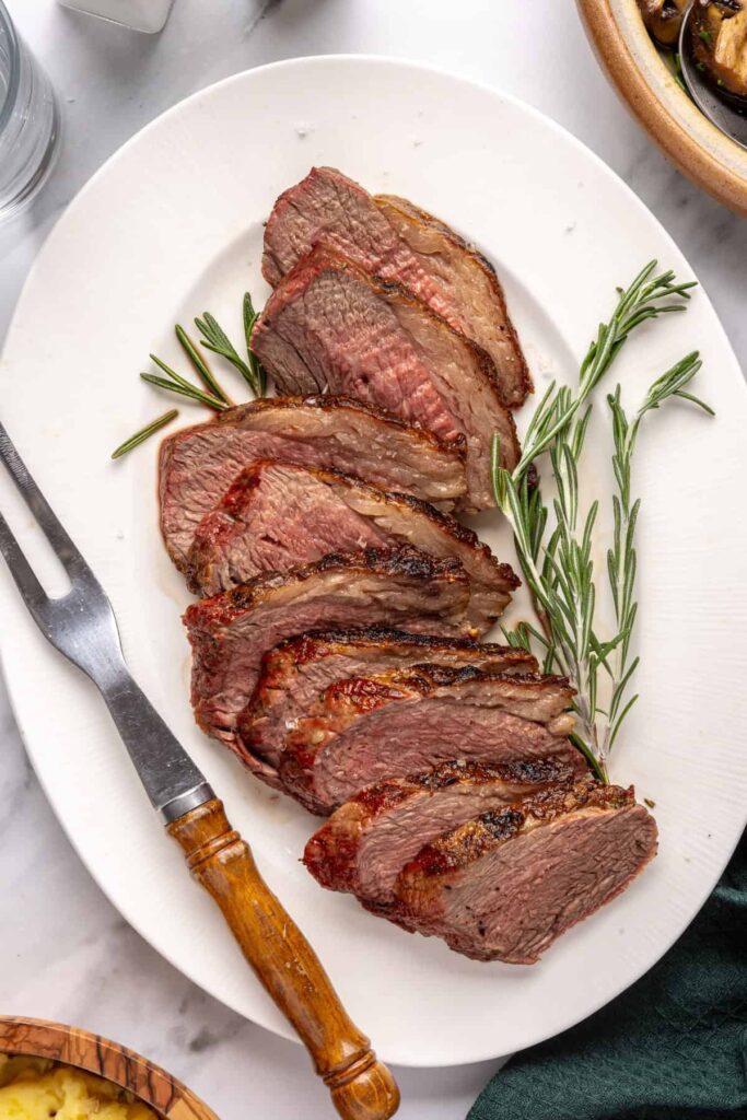 Grilled tri-tip steak seasoned with rosemary, salt, and pepper, sliced and ready to serve