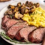 Tri-tip steak served with creamy mashed potatoes and garlicky sautéed mushrooms on a plate, steakhouse-style dinner