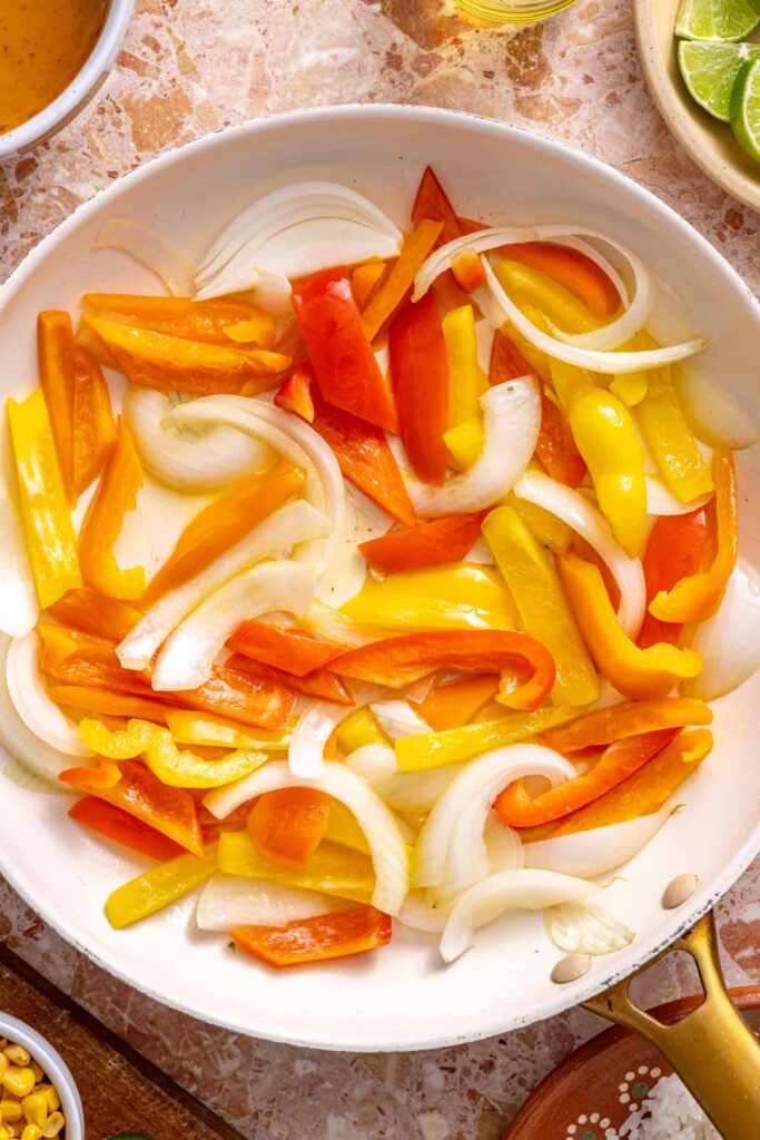 Colorful bell peppers and onions cooking in pan