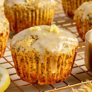 Healthy, protein-packed lemon poppy seed muffins on a baking rack with a drizzle of dairy-free lemon glaze.