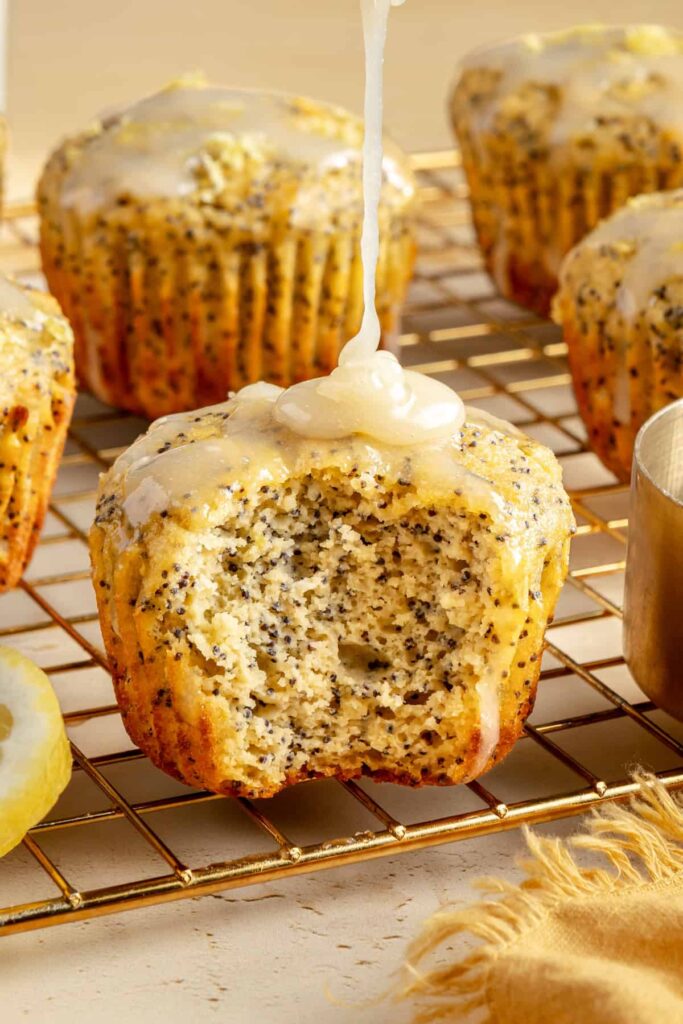 Healthy, protein-packed lemon poppy seed muffins on a baking rack with a drizzle of dairy-free lemon glaze.