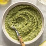 Homemade basil pesto recipe served in white bowl on styled table