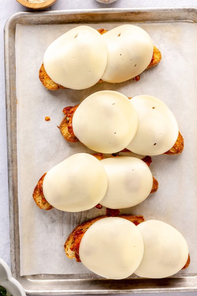 Open-faced, high-protein chicken pesto parmesan meatball subs with marinara sauce and melted cheese