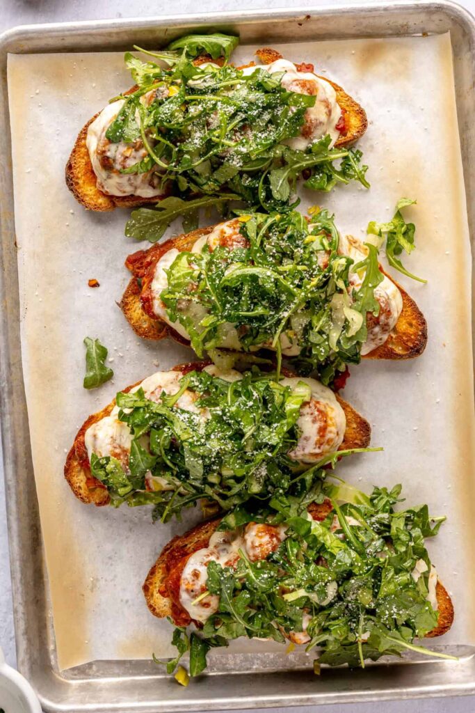 Open-faced, high-protein chicken pesto parmesan meatball subs with marinara sauce and melted cheese
