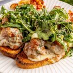 Open-faced, high-protein chicken pesto parmesan meatball subs with marinara sauce and melted cheese
