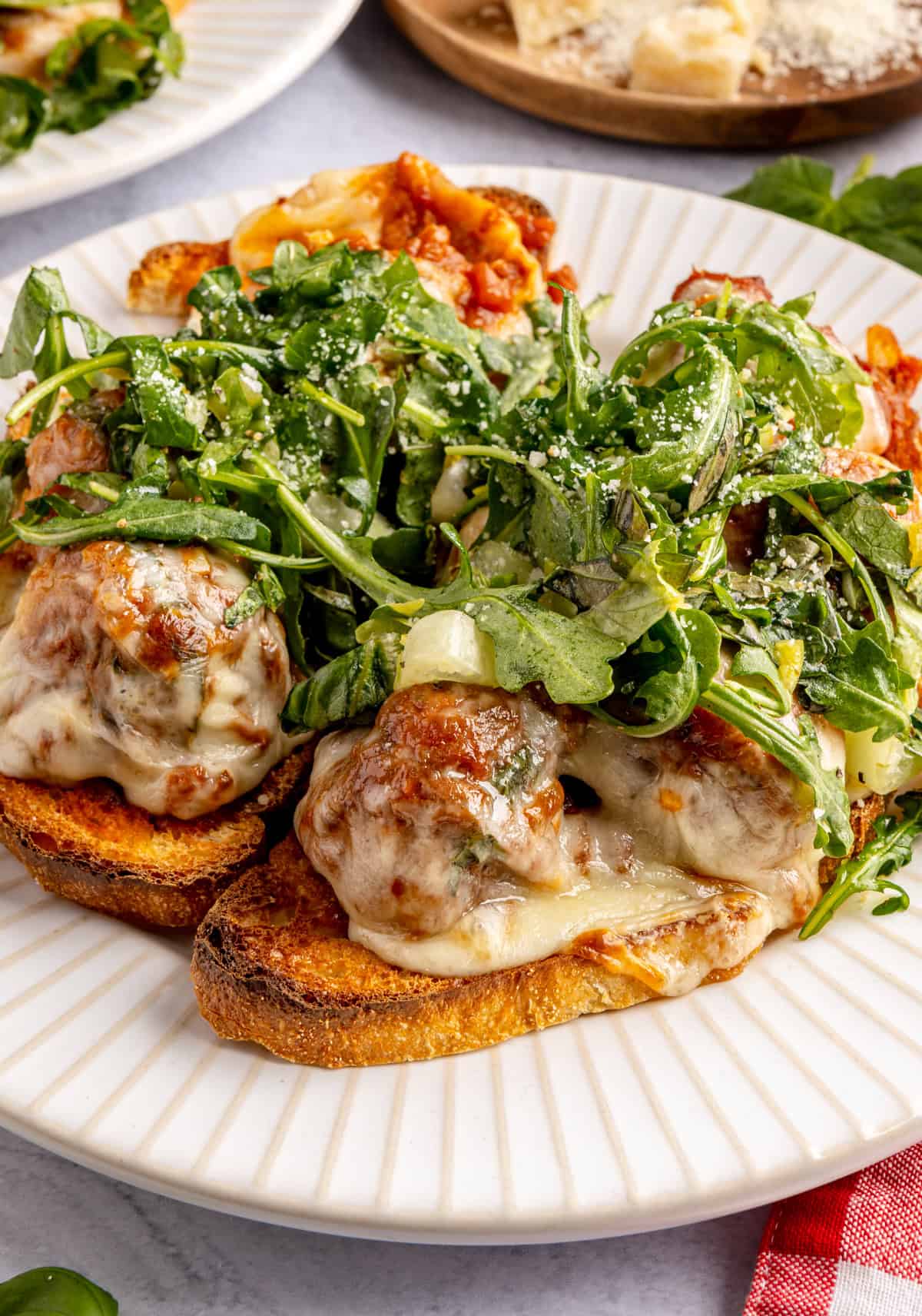 Open-faced, high-protein chicken pesto parmesan meatball subs with marinara sauce and melted cheese