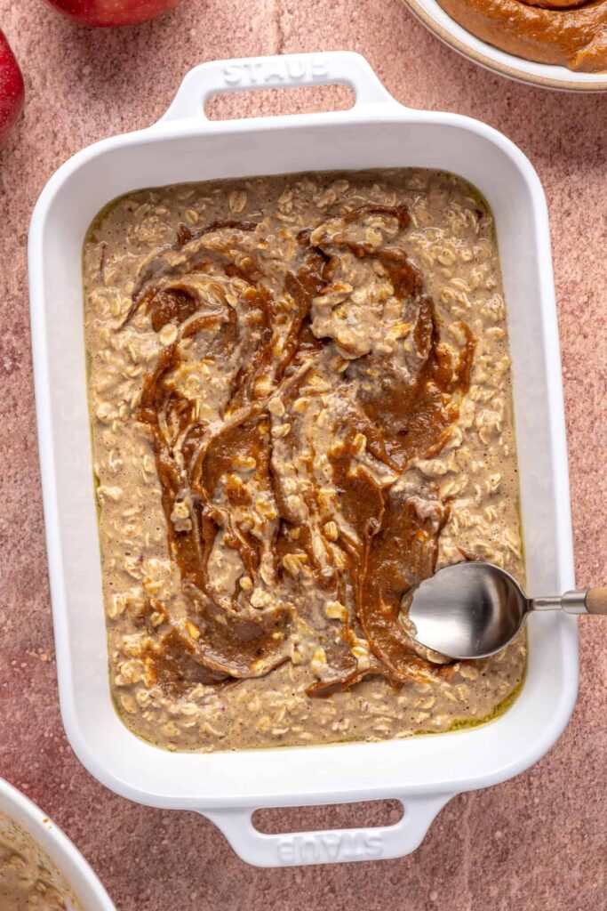 swirling date caramel into high-protein oatmeal batter for baked apple oatmeal in a baking dish