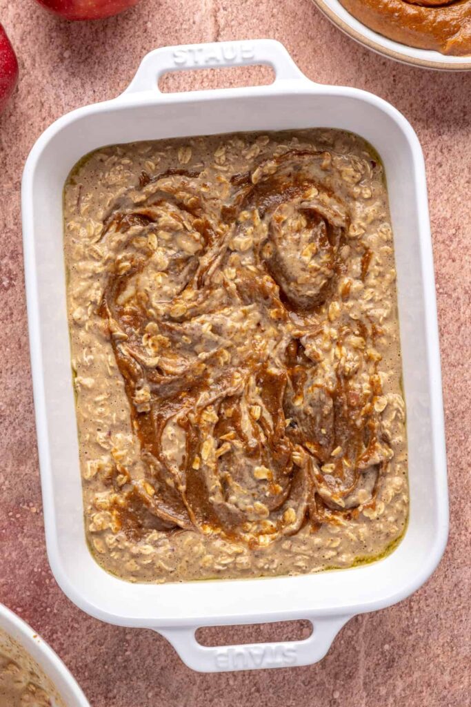 High-protein oatmeal batter for baked apple oatmeal in a baking dish, with date caramel swirled in