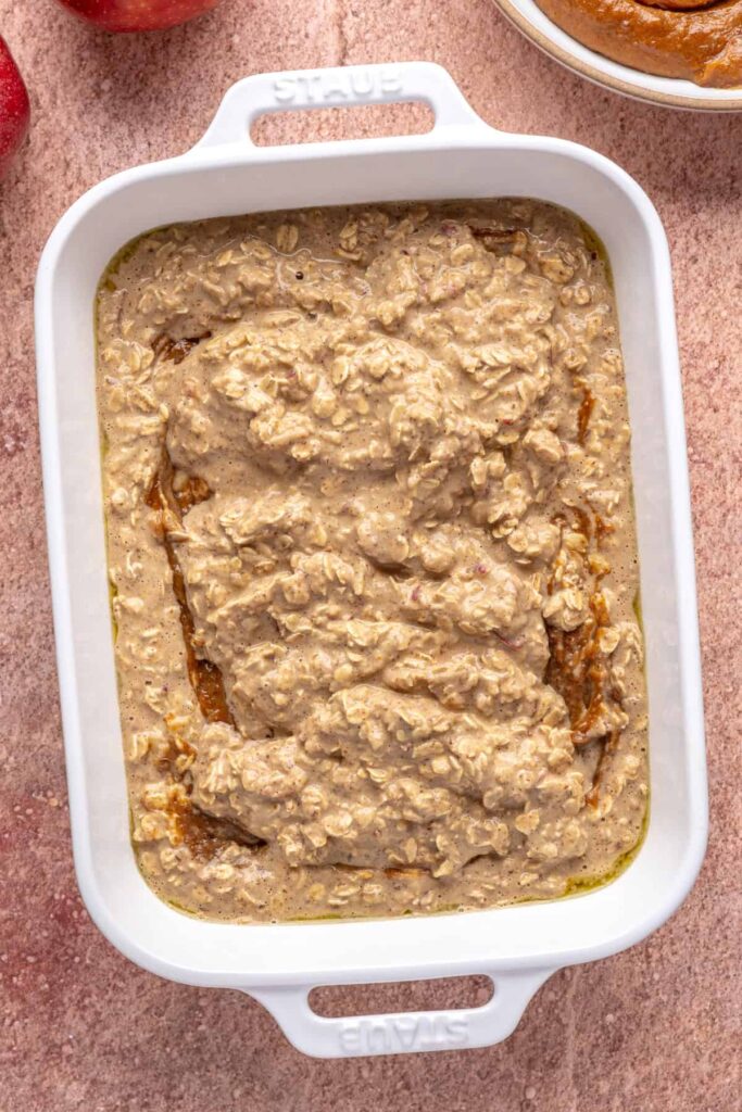 layering high-protein oatmeal batter for baked apple oatmeal in a baking dish