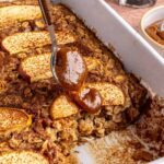 Side view of baked apple oatmeal in baking dish, caramel and apples on top