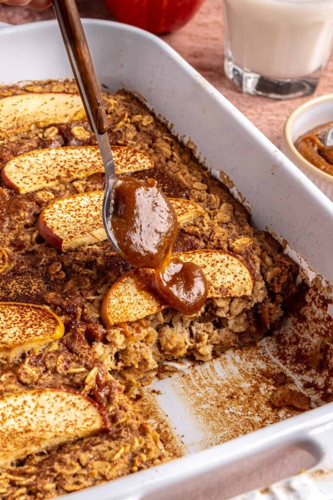 Side view of baked apple oatmeal in baking dish, caramel and apples on top