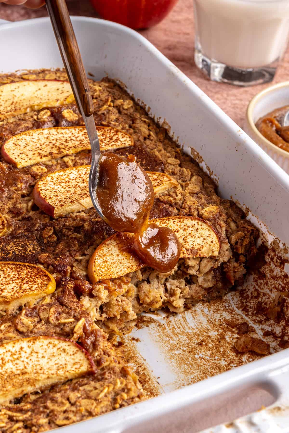 Side view of baked apple oatmeal in baking dish, caramel and apples on top