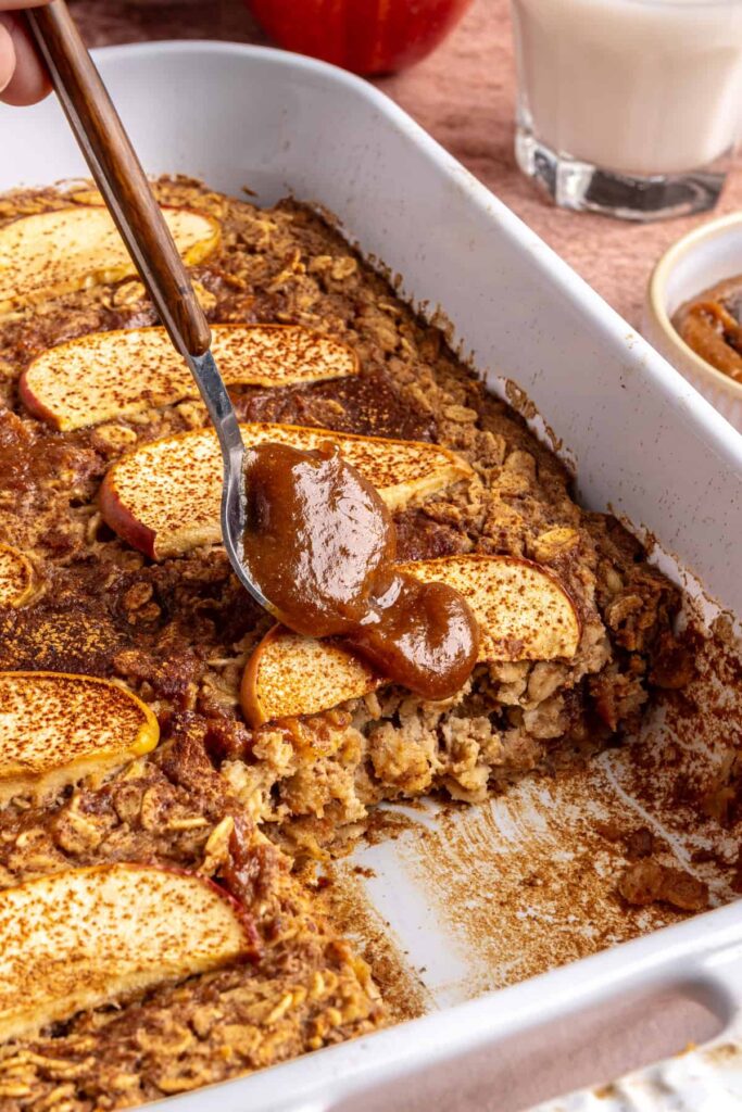 Side view of baked apple oatmeal in baking dish, caramel and apples on top