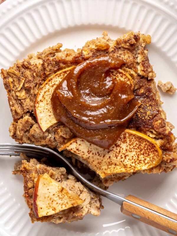 close up of a slice of baked apple oatmeal with caramel on a white plate, cozy breakfast